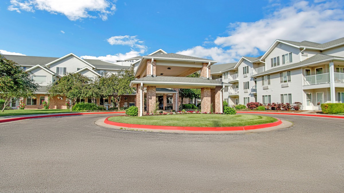 A large residential building with landscaped surroundings under a partly cloudy sky.