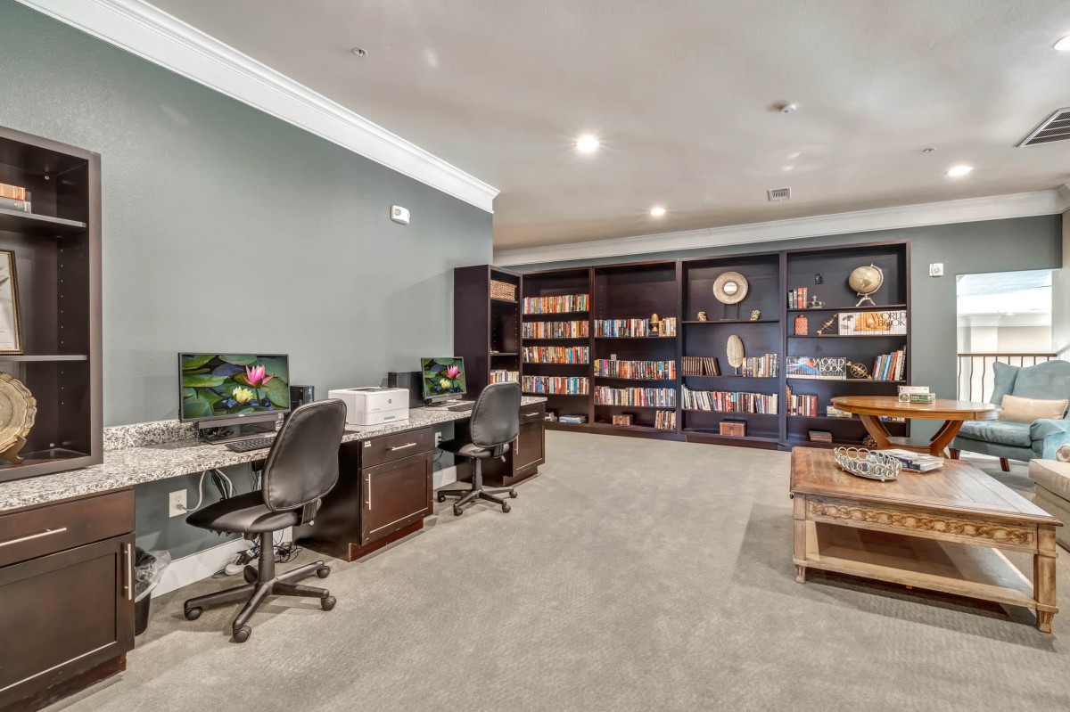 A spacious home office with bookshelves and a dual desk setup.