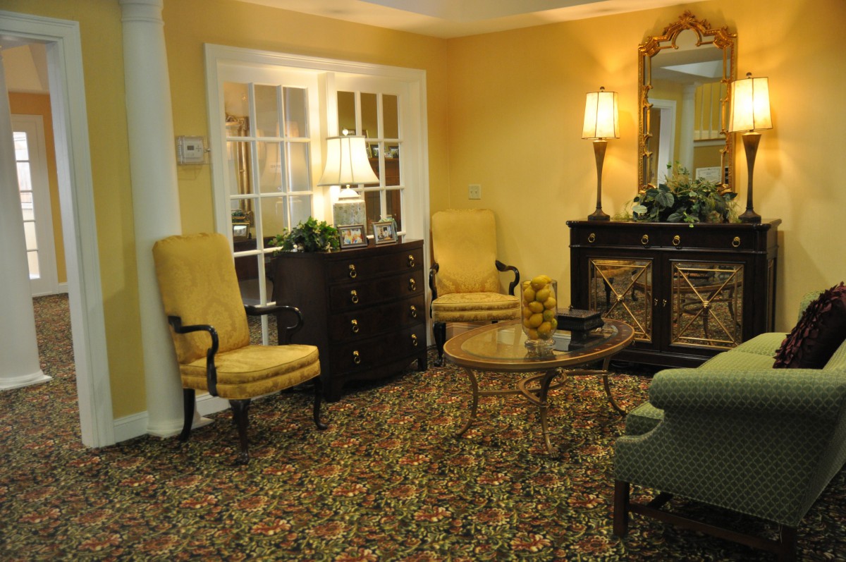 A cozy living room with yellow walls, featuring classic furniture and warm lighting.