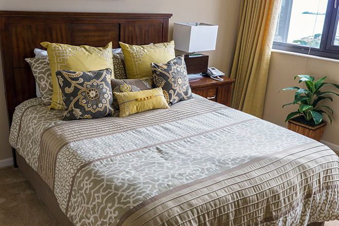 A cozy bedroom with a neatly arranged bed and decorative pillows.