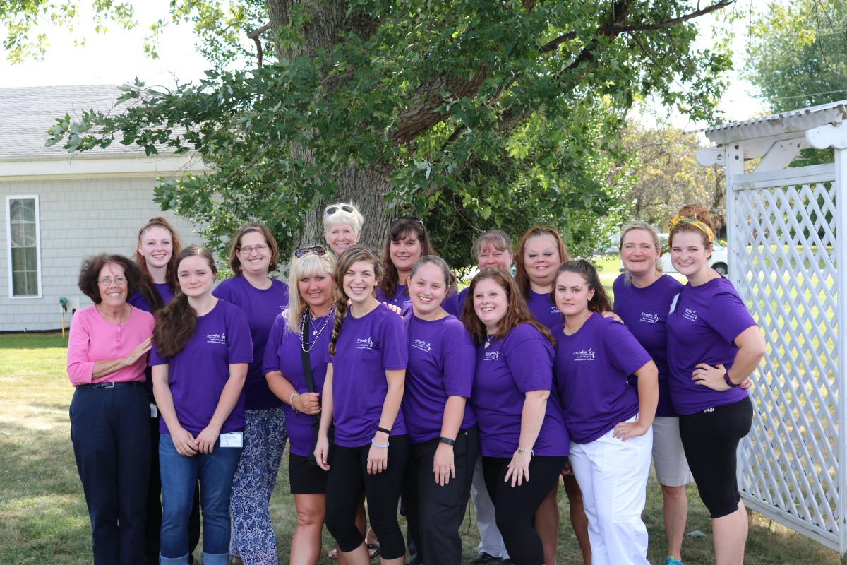 A group of people wearing purple shirts posing together outdoors.