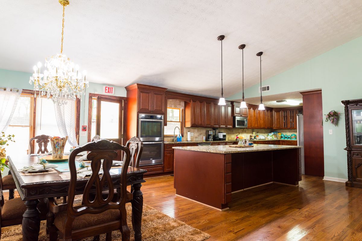Spacious kitchen and dining area with wood flooring and elegant pendant lighting.