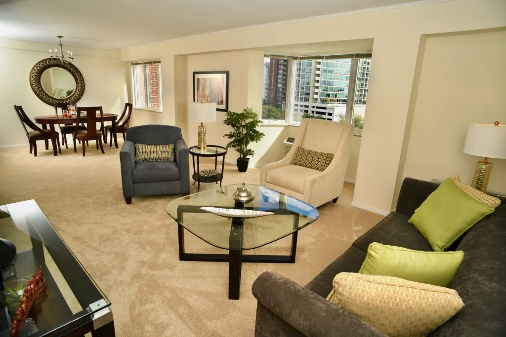 A modern living room with stylish furniture and a cityscape view through large windows.