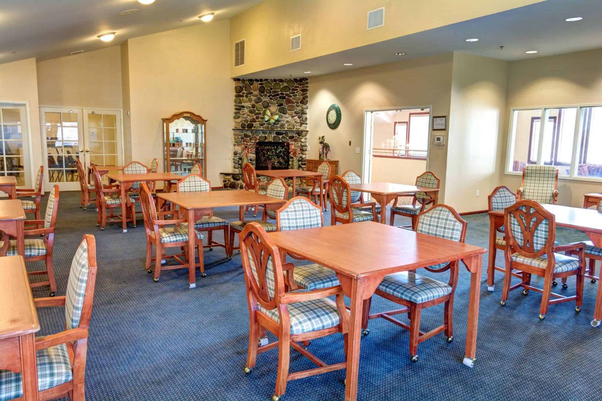 A spacious dining area with wooden tables and chairs, featuring a stone fireplace and elegant decor.