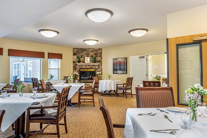A cozy dining room with neatly arranged tables and a central fireplace, creating a welcoming atmosphere.