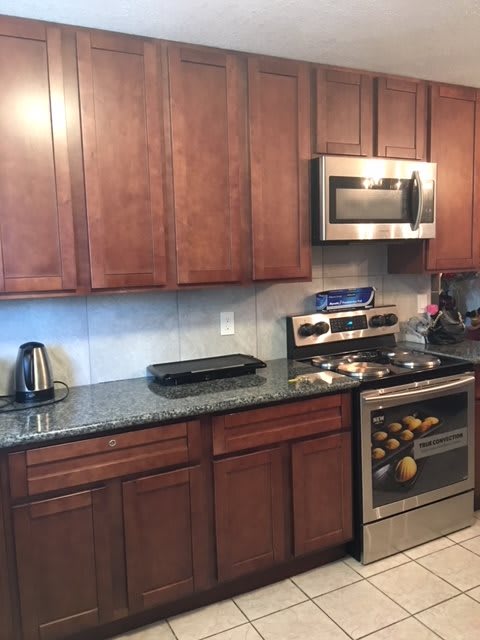 A modern kitchen with wooden cabinets, stainless steel appliances, and a granite countertop.