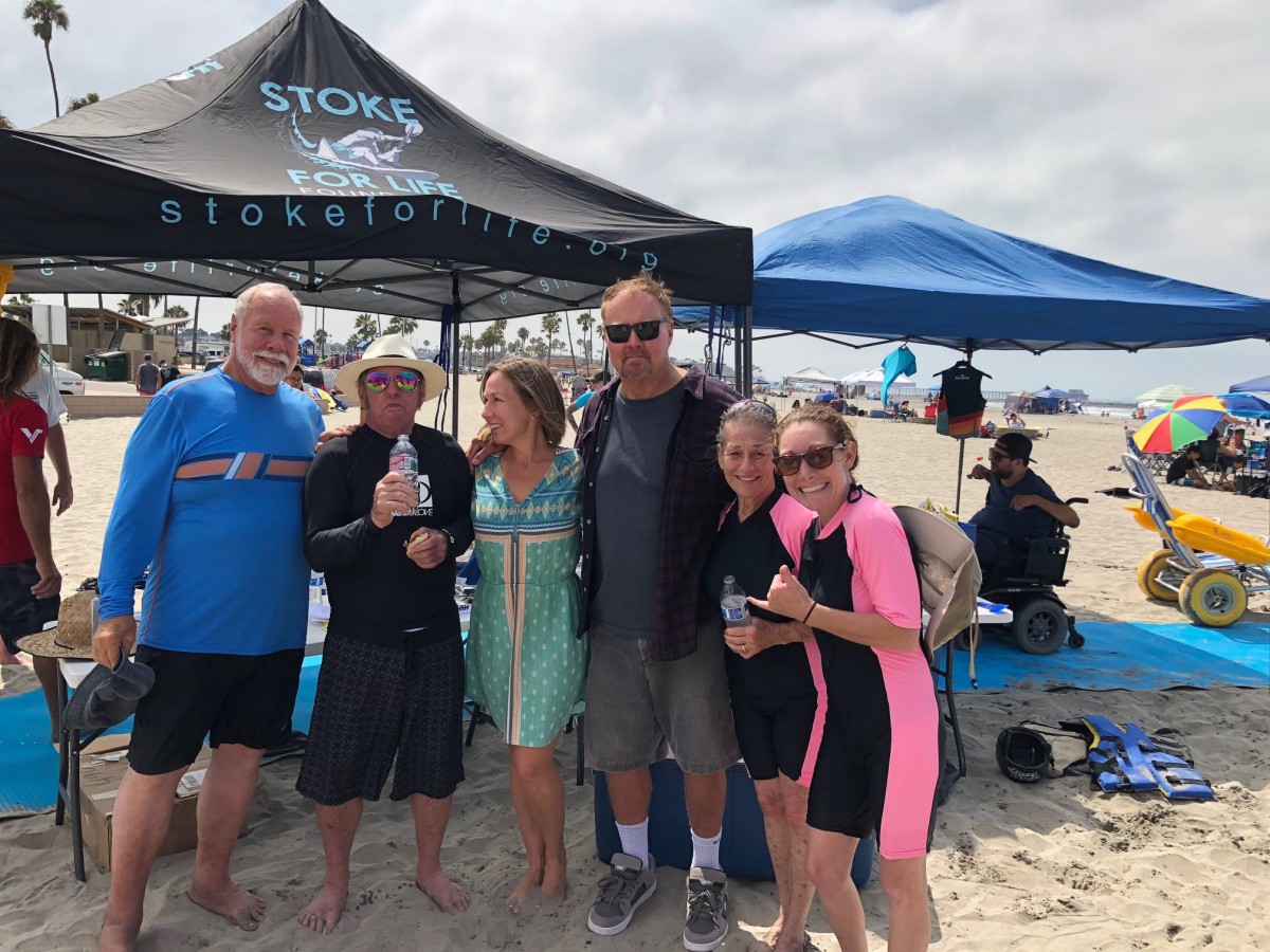 A group of people enjoying a day at the beach under a tent.
