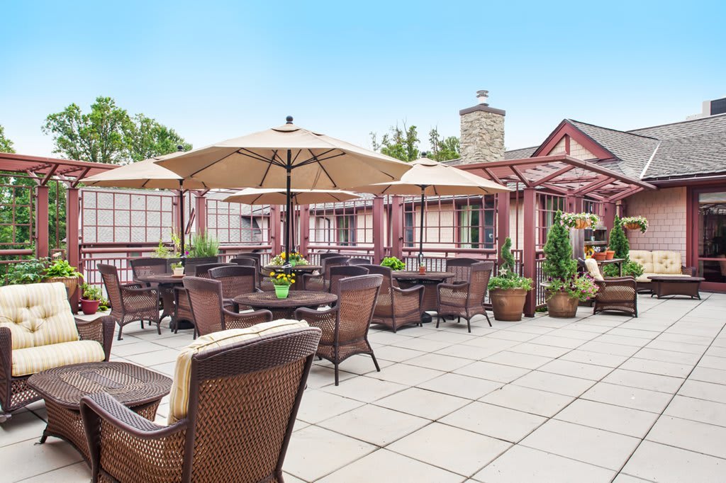 A cozy outdoor patio with wicker furniture and umbrellas, perfect for dining or relaxing in a charming restaurant setting.