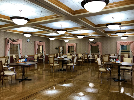 A spacious and elegantly designed dining room featuring wooden floors, well-arranged tables, and modern lighting fixtures.