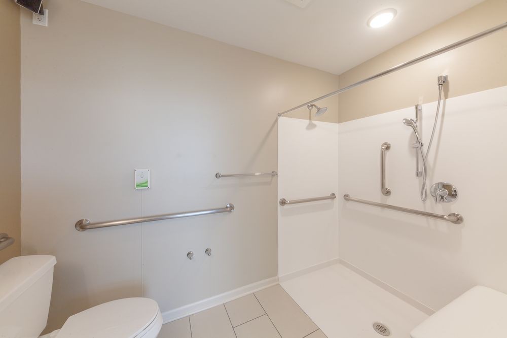 An accessible bathroom with a shower area and grab bars.