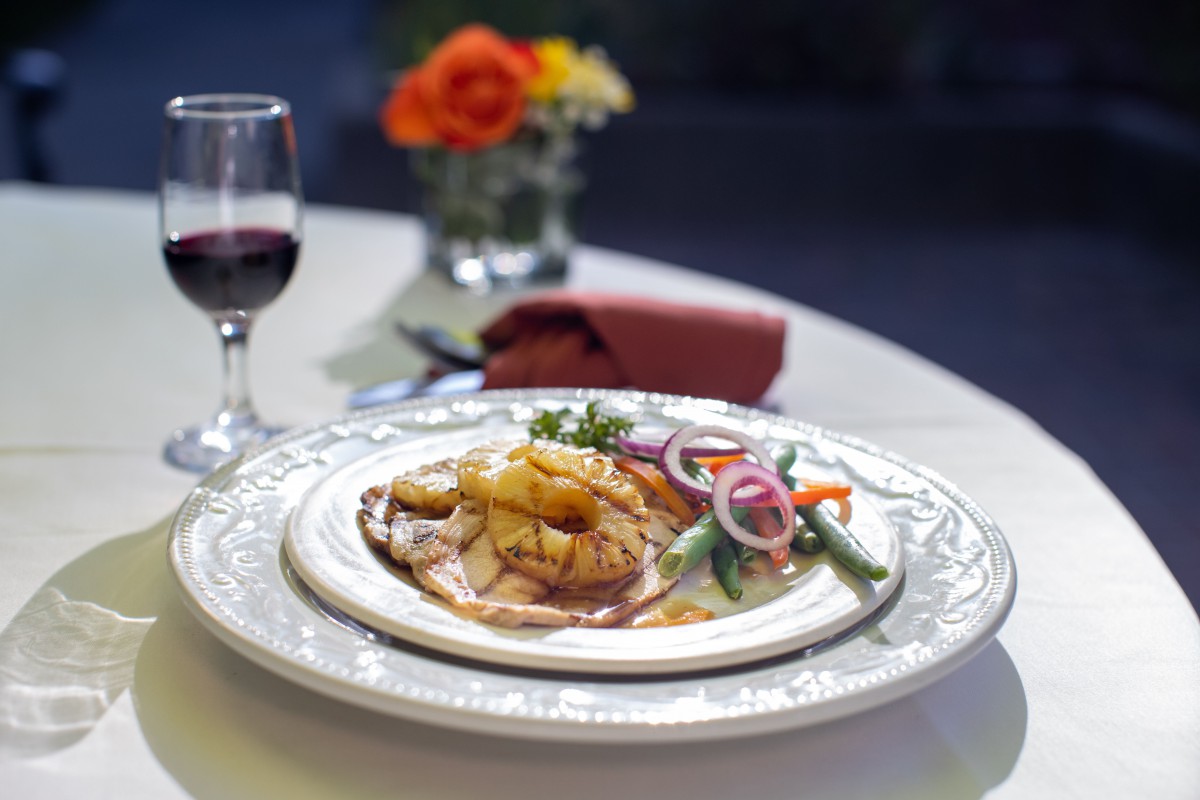 A gourmet meal served at a fine dining restaurant with wine and flowers adorning the table.
