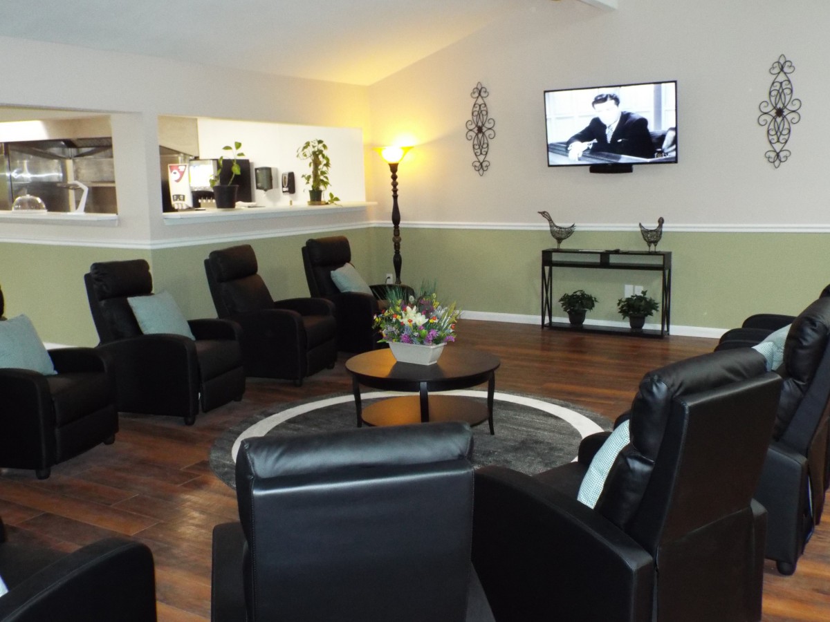A modern living room with leather chairs arranged around a TV, featuring wood flooring and contemporary decor.