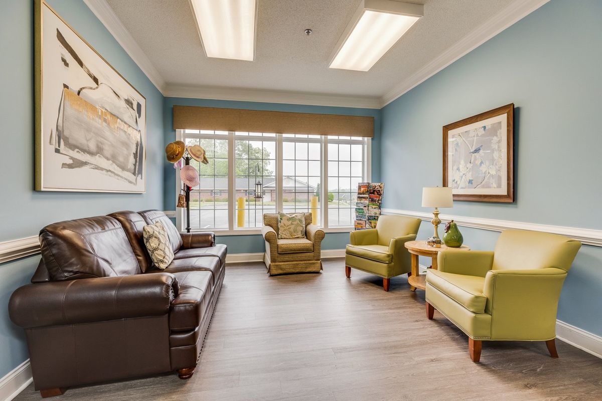A cozy living room with a sofa, two armchairs, and large windows allowing abundant natural light.