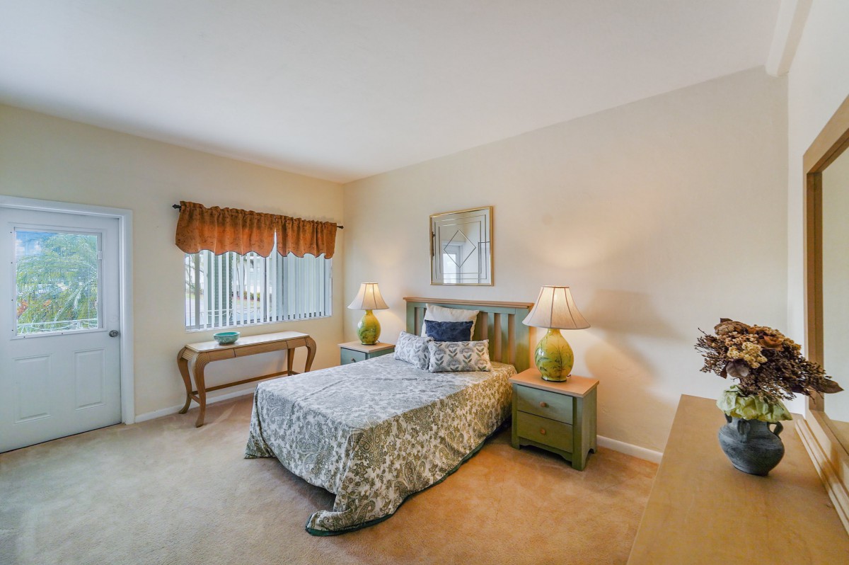 A cozy bedroom with a neatly made bed, two nightstands with lamps, and a window adorned with curtains.
