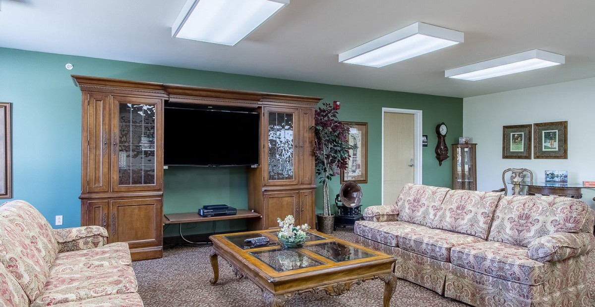 A cozy living room setup with a plaid sofa, wooden TV stand, glass-top coffee table, and decorative elements.
