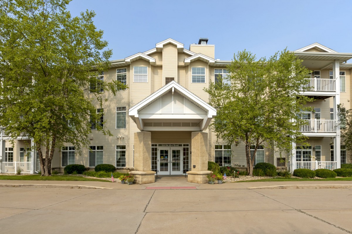 A front view of a residential building with trees flanking the entrance.