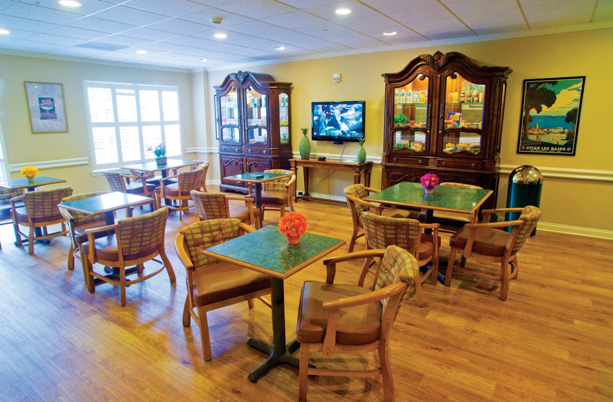 A cozy dining area with wooden tables and chairs, featuring a television and elegant cabinets.