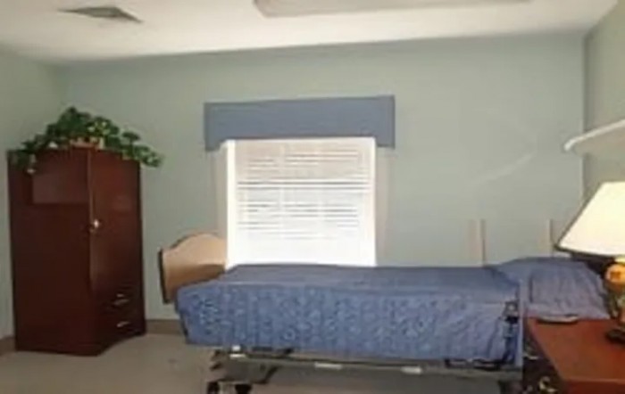 A simple hospital room with a single bed and a window with closed blinds.