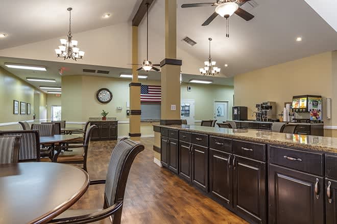 A spacious kitchen and dining area featuring dark wood cabinets, multiple chandeliers, and comfortable seating.