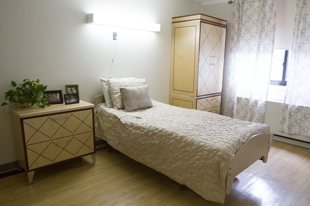 A minimalist bedroom featuring a single bed and light wooden furniture.