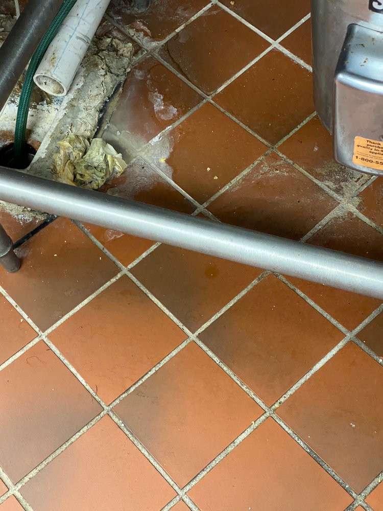 A kitchen floor with tiles and a visible spill being cleaned.