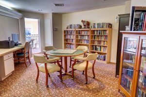 A cozy library with a round table surrounded by chairs, and bookshelves lining the walls.