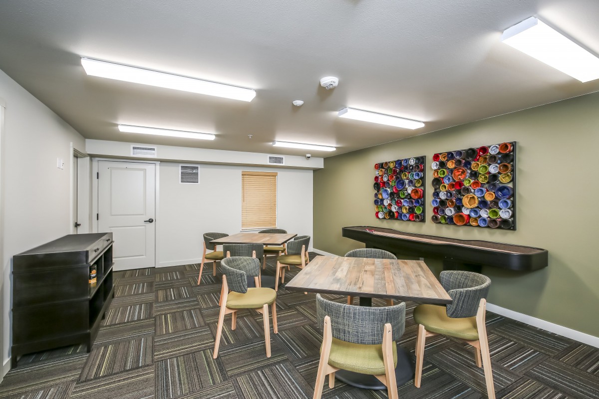 A modern meeting room with tables, chairs, and colorful artwork on the wall.