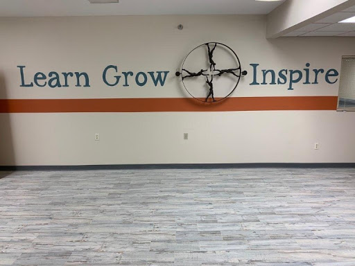 A wall featuring the words 'Learn, Grow, Inspire' accompanied by a decorative element in a modern interior space.