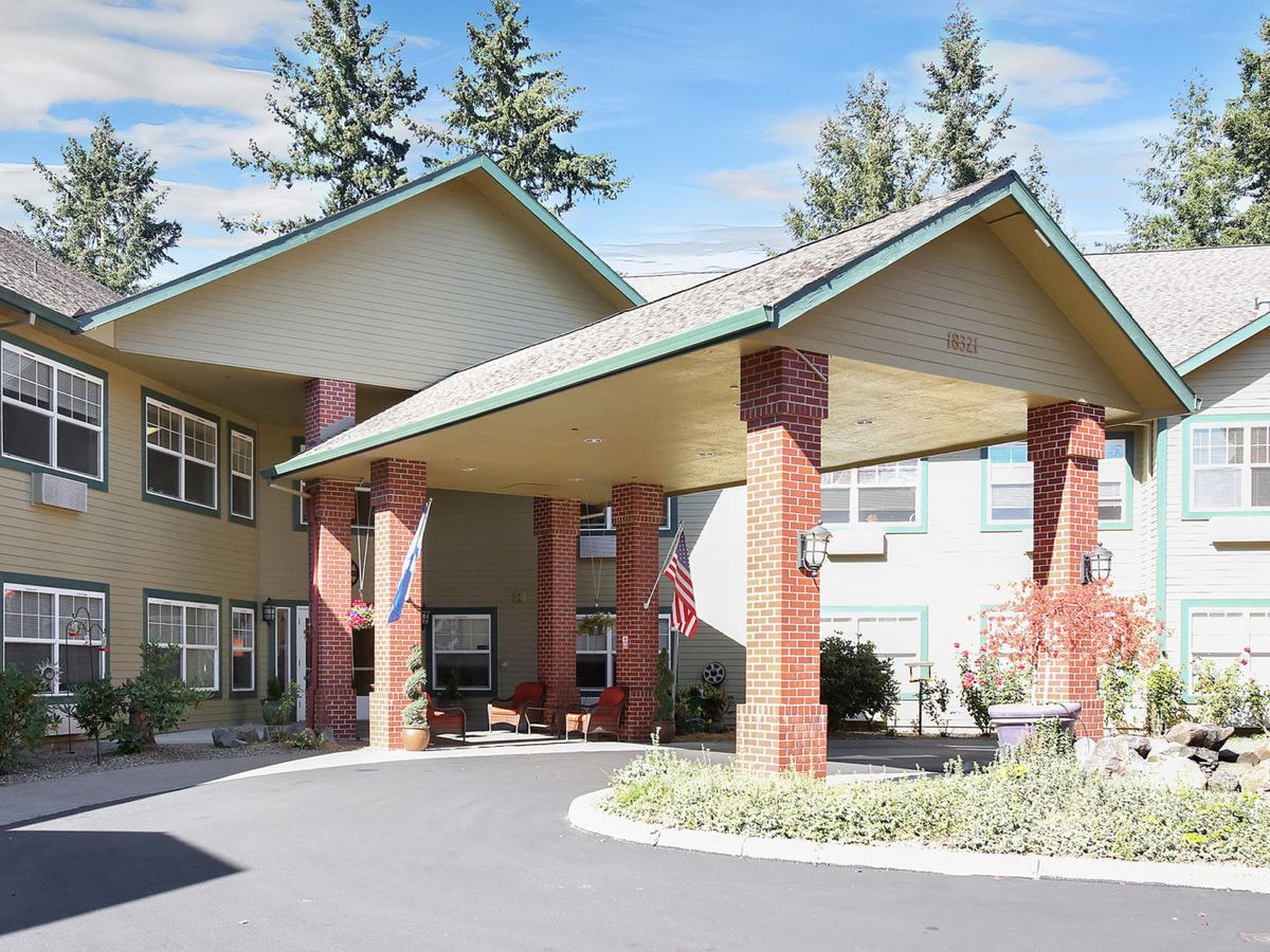 An inviting building entrance with a covered driveway and surrounded by trees.