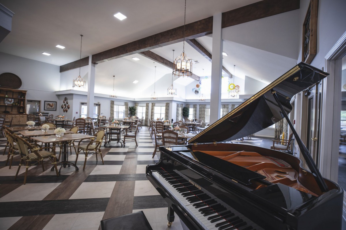 An elegant restaurant interior featuring a grand piano and neatly arranged tables and chairs.