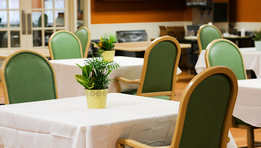 A cozy dining area featuring tables with white tablecloths and small potted plants.
