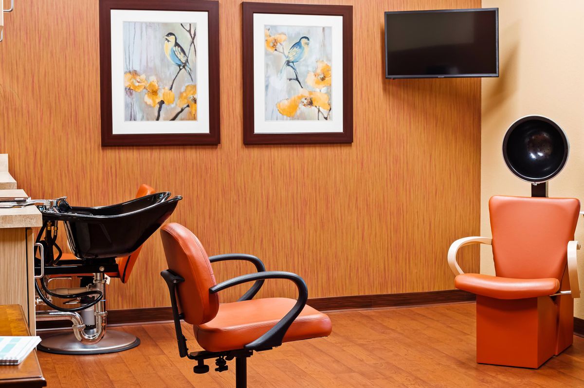 A cozy salon interior with orange chairs, wall art, and a television.