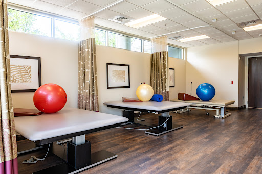 A well-equipped therapy room featuring exercise balls and adjustable tables, designed for rehabilitation and fitness.