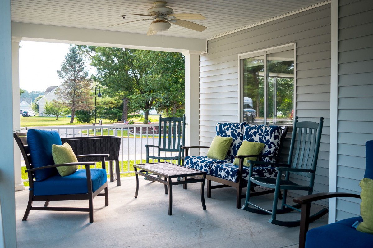 A cozy porch with comfortable seating and a table, perfect for a relaxing sunny day.