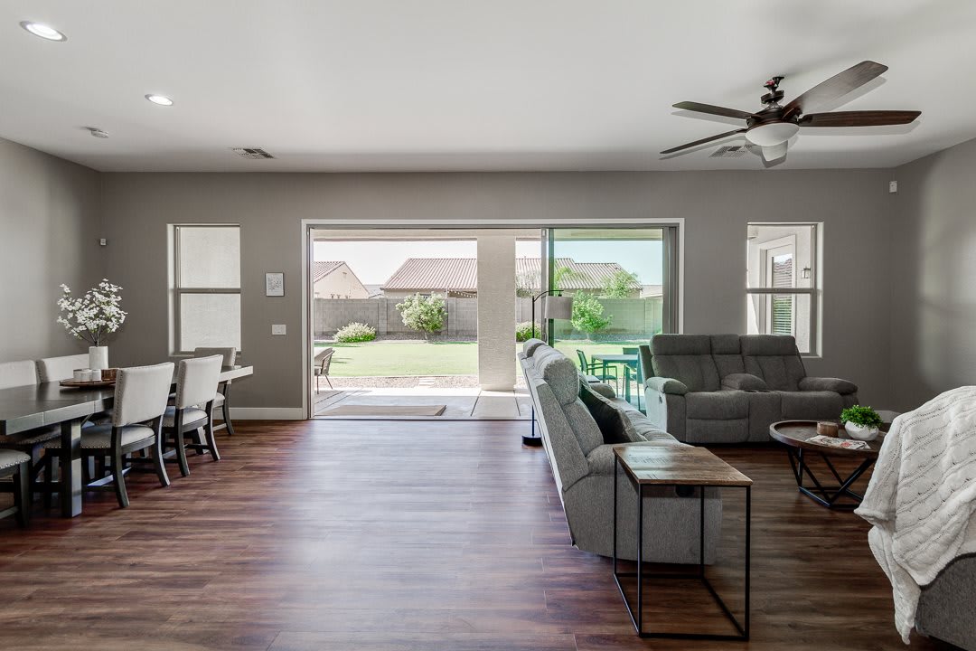 A spacious modern living room with sleek furniture, a dining area, and large patio doors letting in natural light.
