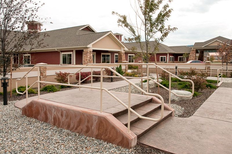 A residential building with a landscaped entrance featuring stairs and railings.