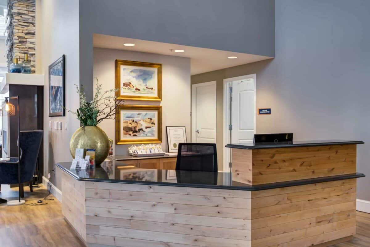 A modern reception area with a wooden desk and decorative artwork on the walls.