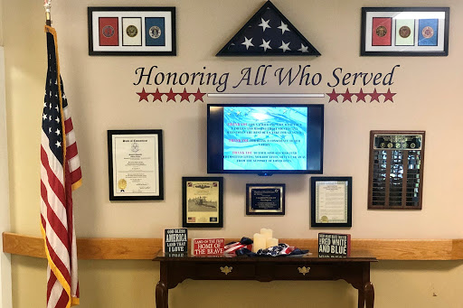 A tribute wall dedicated to honoring all who have served in the military, showcasing various awards and certificates.