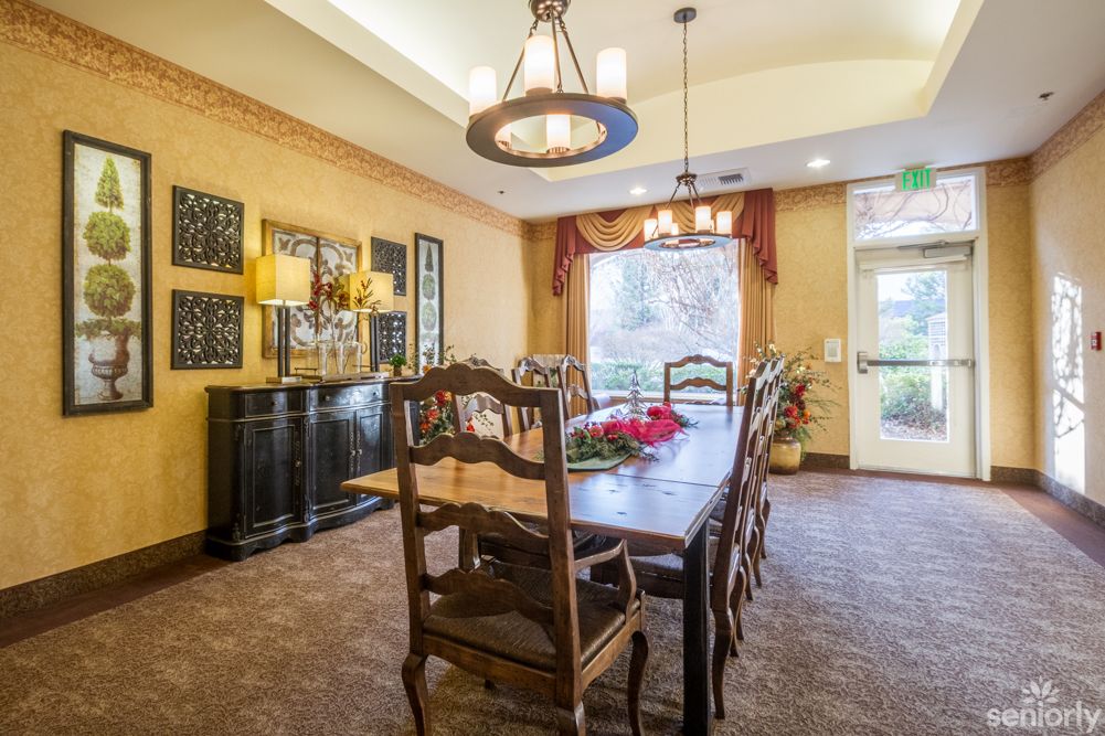 A cozy dining room with an elegant wooden table and chairs, illuminated by a chandelier.