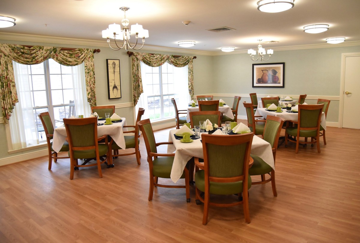 An elegantly furnished dining room with neatly arranged tables and chairs, featuring large windows and tasteful decor.