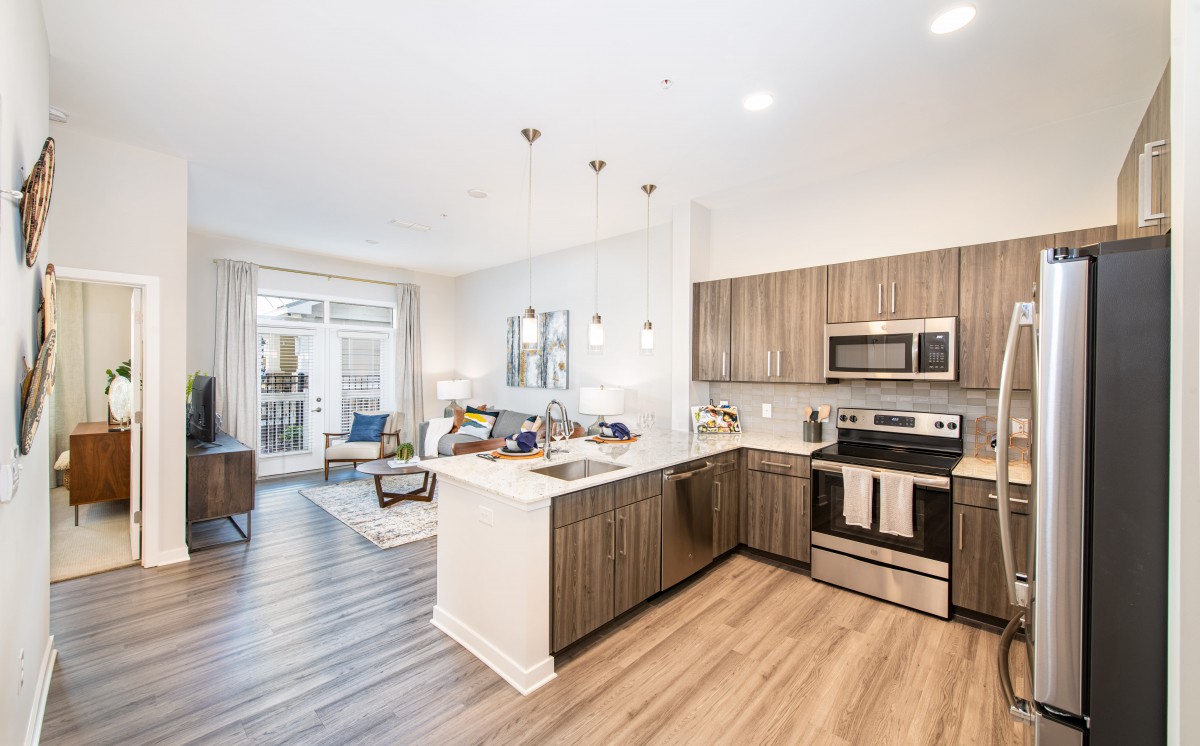 A modern open-concept kitchen and living area featuring wood flooring and stainless steel appliances.