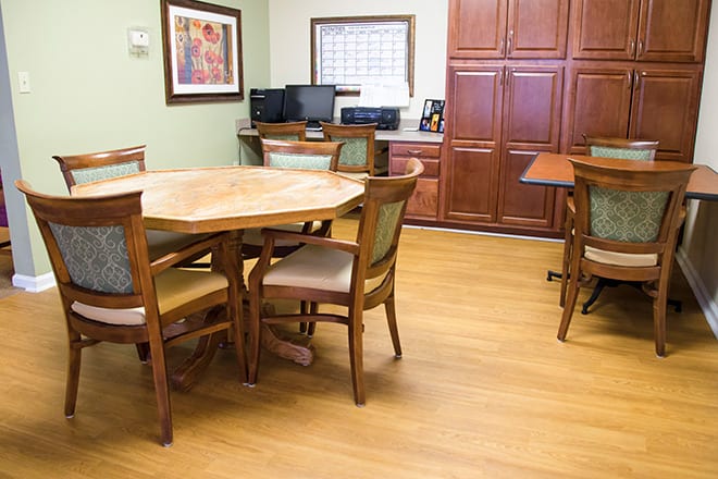 A small meeting room with a round conference table, chairs, and office equipment.