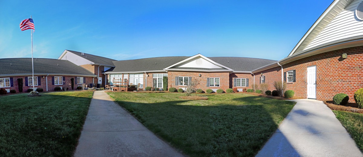 A single-story brick building with a well-maintained lawn and clear blue sky.