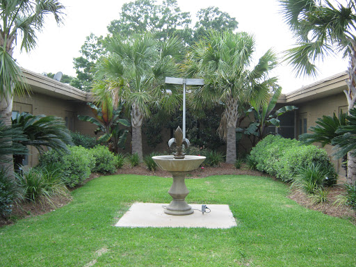 A serene garden featuring a central fountain surrounded by lush palm trees.