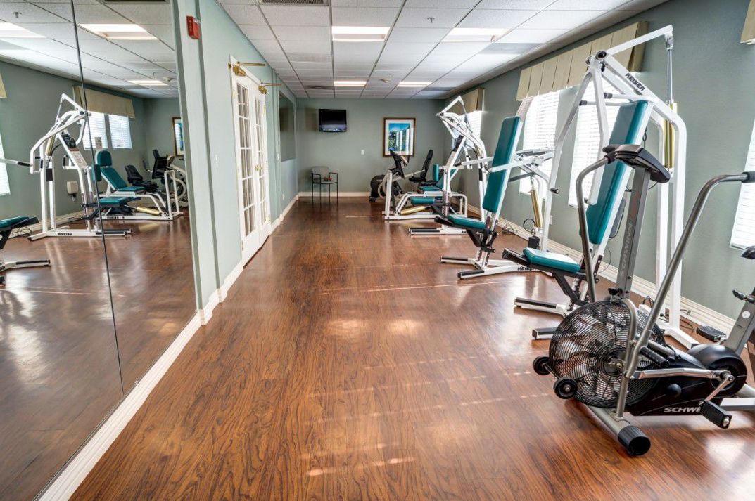 A spacious gym with various fitness machines and a wooden floor.