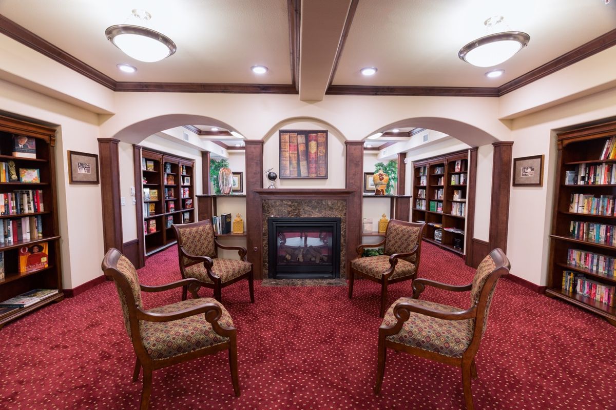 A cozy library seating area with a fireplace and bookshelves.