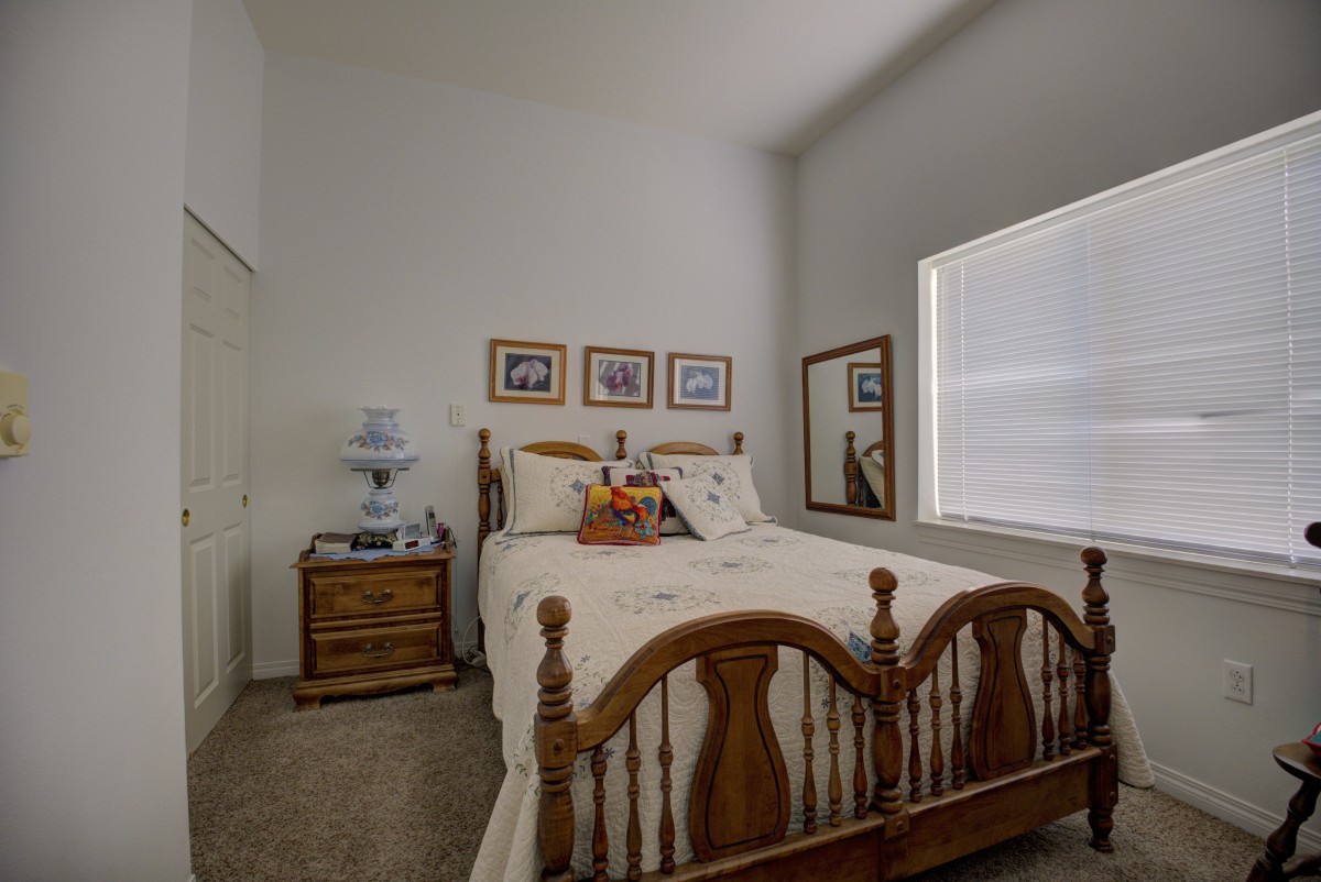 A cozy bedroom with a wooden bed, side table, and decorative elements.