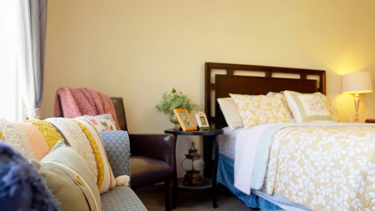 A cozy bedroom with a neatly made bed and decorative pillows.