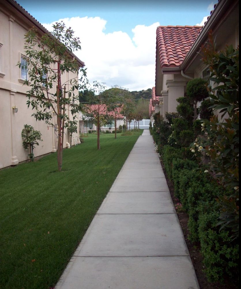 A suburban walkway lined with buildings and greenery.