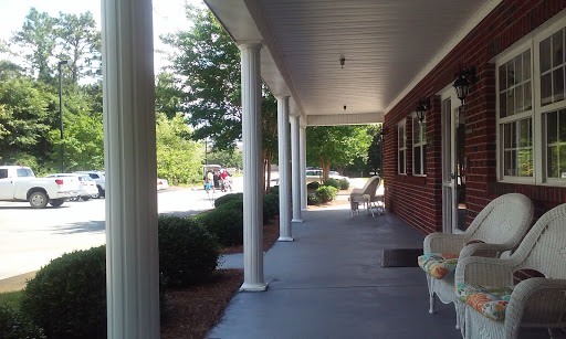 A peaceful porch view with columns and surrounding greenery.